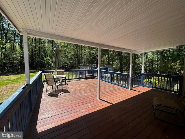 deck with a lawn, an outbuilding, a storage shed, and outdoor dining space