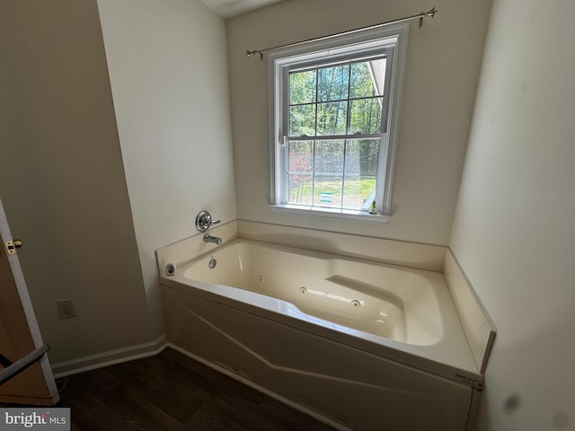 full bathroom featuring baseboards, a tub with jets, and wood finished floors