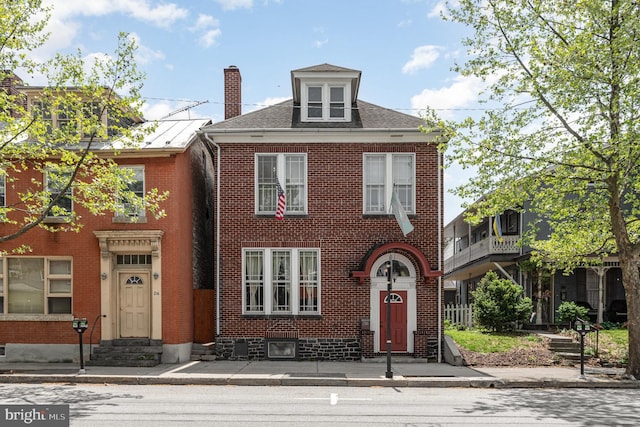 view of front of property featuring entry steps, a chimney, a shingled roof, and brick siding