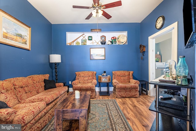living room with baseboards, a ceiling fan, and wood finished floors