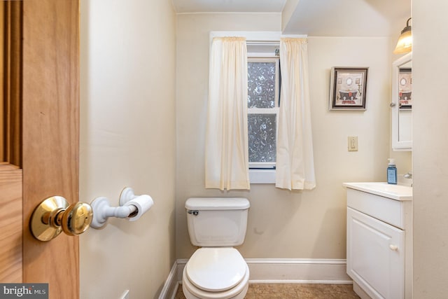 bathroom featuring baseboards, vanity, and toilet