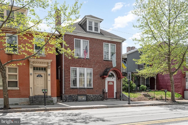view of front of house featuring brick siding, a chimney, and entry steps