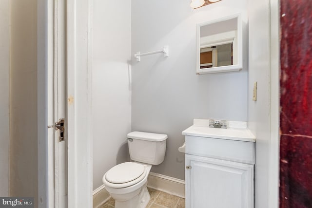 half bath with tile patterned floors, baseboards, vanity, and toilet
