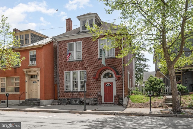 view of front of house with entry steps, a chimney, and brick siding