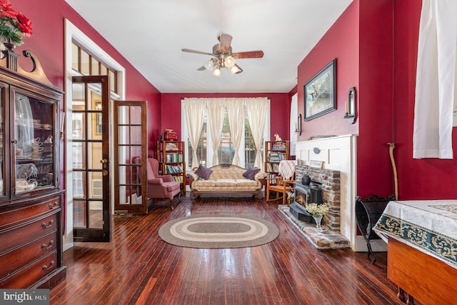living area with a wood stove, ceiling fan, french doors, and hardwood / wood-style flooring