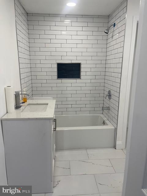 full bath featuring marble finish floor, washtub / shower combination, and vanity