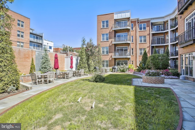 view of community featuring a lawn and a patio area