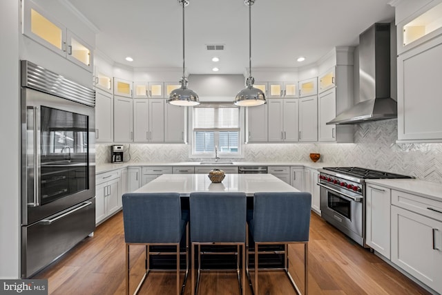 13 N Vendome Ave, Margate City, NJ 08402 - kitchen featuring high quality appliances, wall chimney exhaust hood, a sink, a breakfast bar, and light countertops