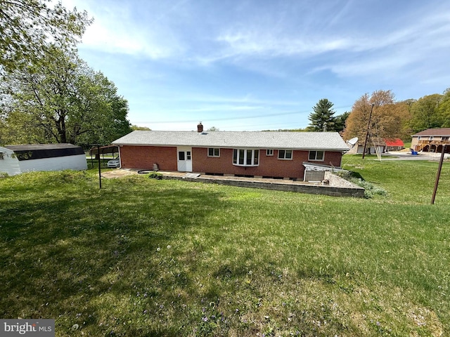 back of house with a yard, brick siding, a chimney, and a patio area