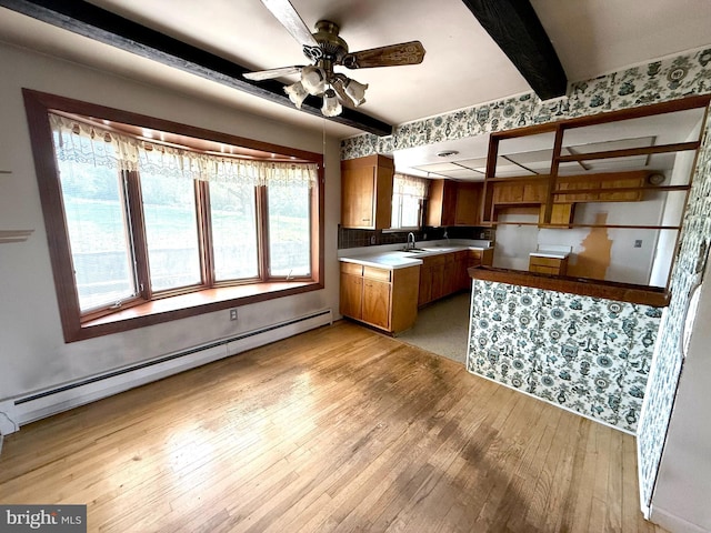 kitchen featuring brown cabinetry, a sink, light wood-style floors, and baseboard heating