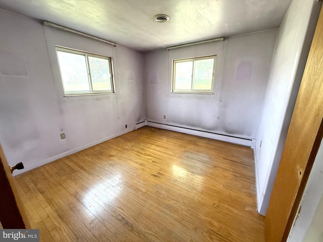 unfurnished room with baseboards, baseboard heating, hardwood / wood-style floors, and a wealth of natural light
