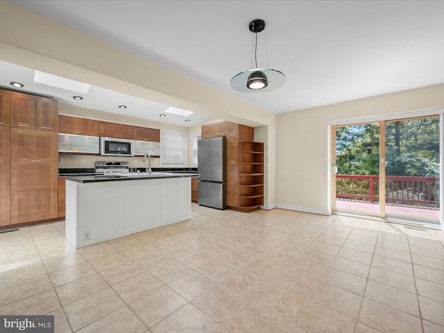kitchen featuring dark countertops, appliances with stainless steel finishes, light tile patterned floors, and a sink