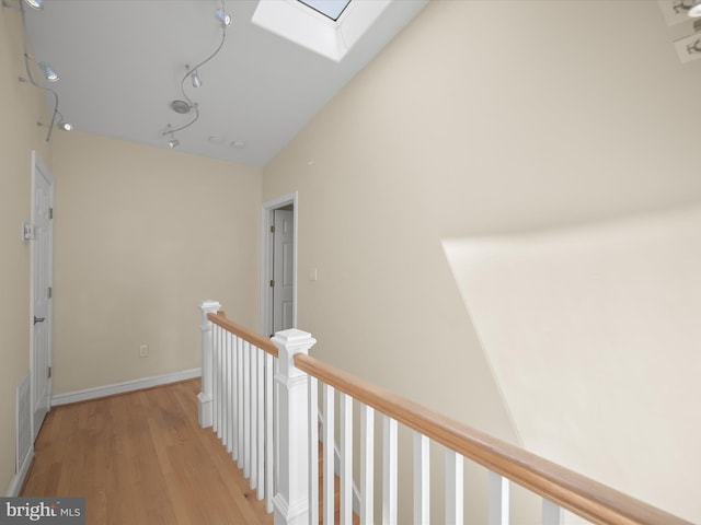 hallway featuring a skylight, an upstairs landing, visible vents, and light wood-style floors