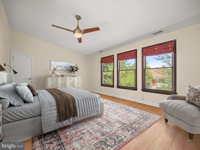 bedroom with visible vents, wood finished floors, vaulted ceiling, and multiple windows