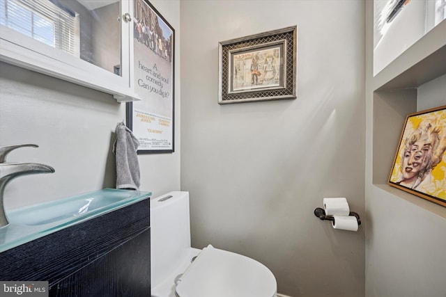 half bathroom with baseboards, toilet, and vanity