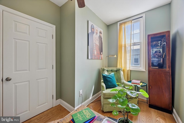 sitting room featuring baseboards, wood finished floors, and ceiling fan