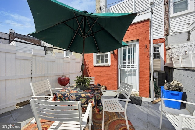 view of patio with outdoor dining space, central AC unit, and fence private yard