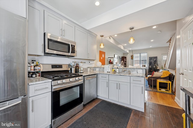 kitchen with recessed lighting, dark wood-style flooring, a peninsula, appliances with stainless steel finishes, and open floor plan