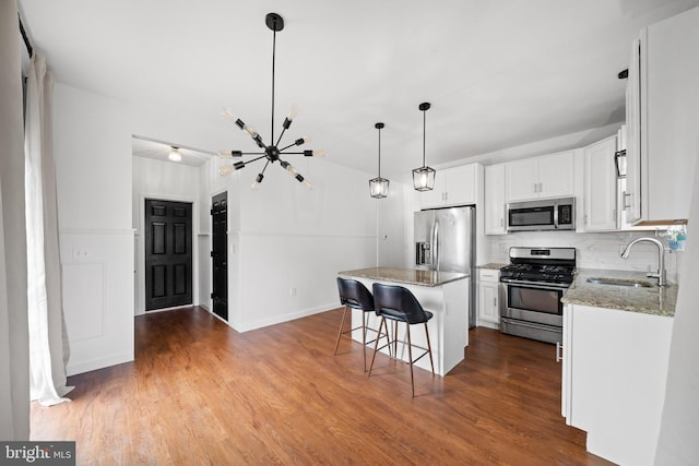 kitchen with white cabinets, appliances with stainless steel finishes, a sink, a chandelier, and tasteful backsplash