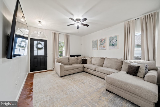 living room with baseboards, ceiling fan, and wood finished floors