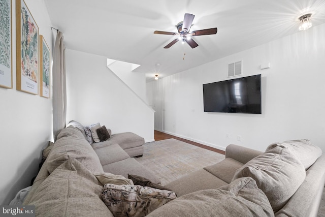 living area with visible vents, a ceiling fan, baseboards, and wood finished floors