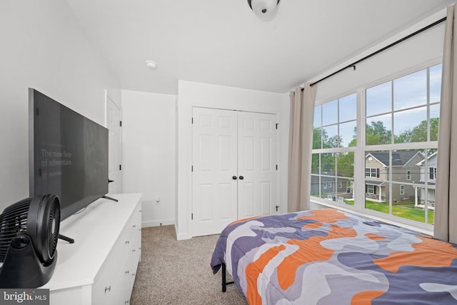 bedroom with baseboards, light carpet, and a closet