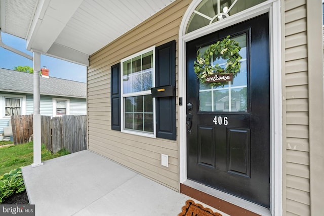 doorway to property with fence and covered porch