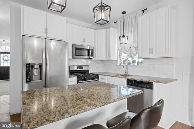 kitchen with white cabinets, light stone countertops, appliances with stainless steel finishes, and a sink