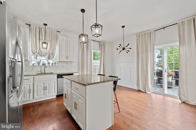 kitchen with a sink, white cabinets, a breakfast bar, and stainless steel appliances