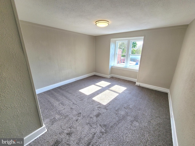 spare room featuring baseboards, a textured ceiling, and carpet