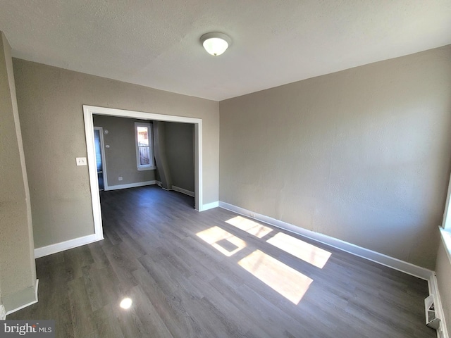 unfurnished room featuring a textured ceiling, wood finished floors, and baseboards