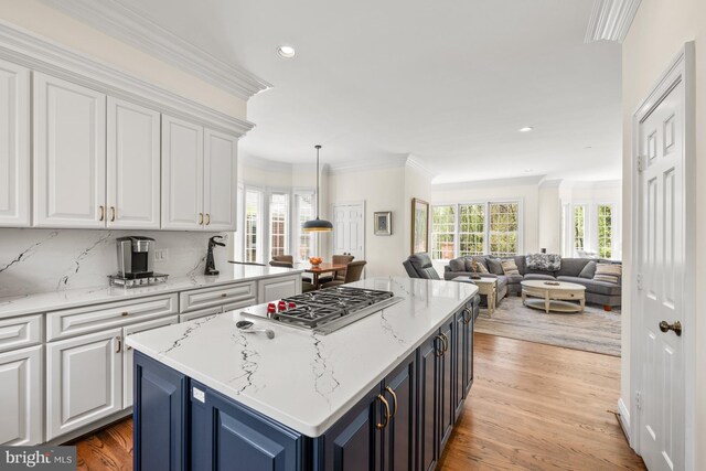 kitchen with stainless steel gas stovetop, white cabinets, a center island, light wood finished floors, and recessed lighting