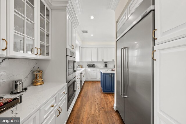 kitchen featuring built in refrigerator, blue cabinets, white cabinetry, ornamental molding, and dark wood-style floors