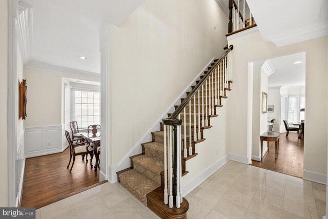 stairs with ornamental molding, arched walkways, wood finished floors, and recessed lighting
