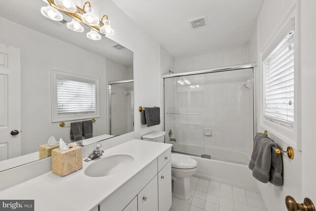 bathroom featuring tile patterned floors, vanity, toilet, and combined bath / shower with glass door