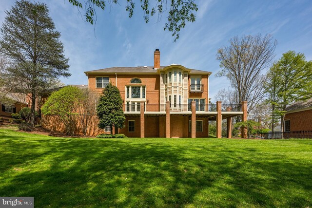 rear view of property with a chimney, a balcony, and brick siding