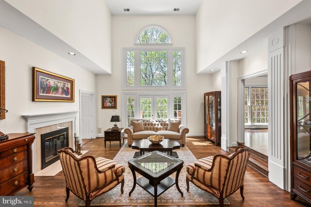living area featuring a towering ceiling, dark wood finished floors, a high end fireplace, and recessed lighting