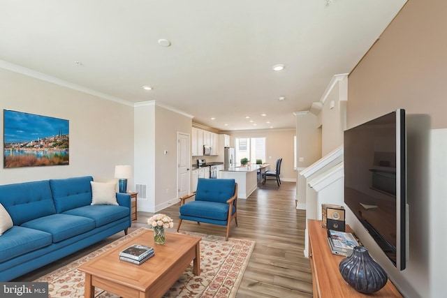 living room with crown molding, baseboards, recessed lighting, and light wood-style flooring