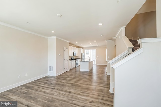 unfurnished living room featuring crown molding, light wood-style floors, recessed lighting, baseboards, and visible vents