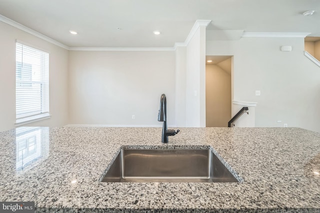 kitchen with a sink, light stone counters, crown molding, and recessed lighting