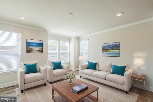 living room featuring baseboards, ornamental molding, visible vents, and light wood-type flooring