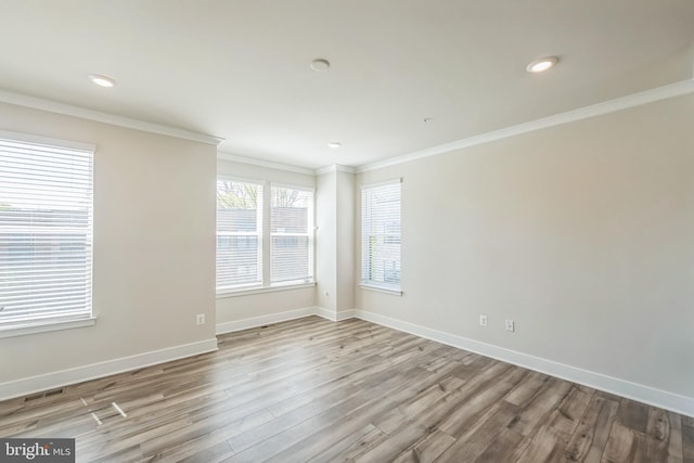 empty room featuring visible vents, wood finished floors, baseboards, ornamental molding, and recessed lighting