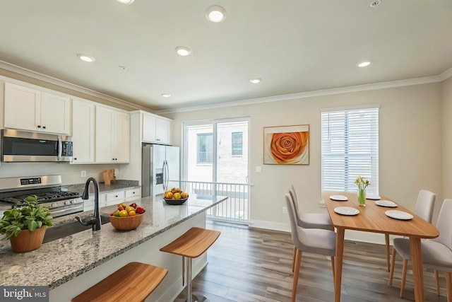 kitchen featuring crown molding, stainless steel appliances, a kitchen breakfast bar, and wood finished floors