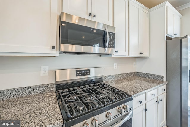 kitchen with stone counters, stainless steel appliances, and white cabinetry