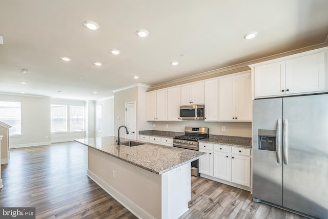 kitchen with appliances with stainless steel finishes, a sink, white cabinets, ornamental molding, and light wood-style flooring