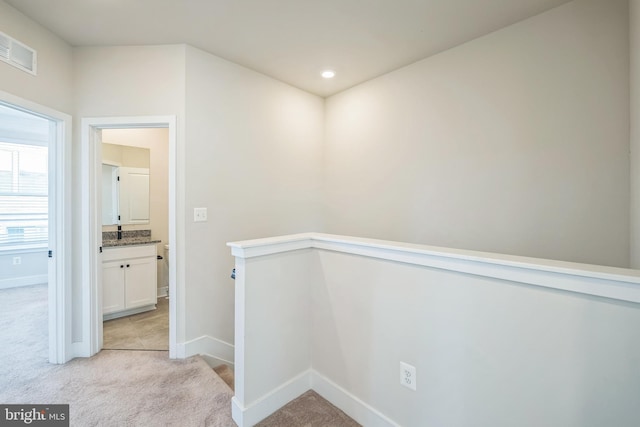 hall featuring baseboards, light carpet, an upstairs landing, and visible vents