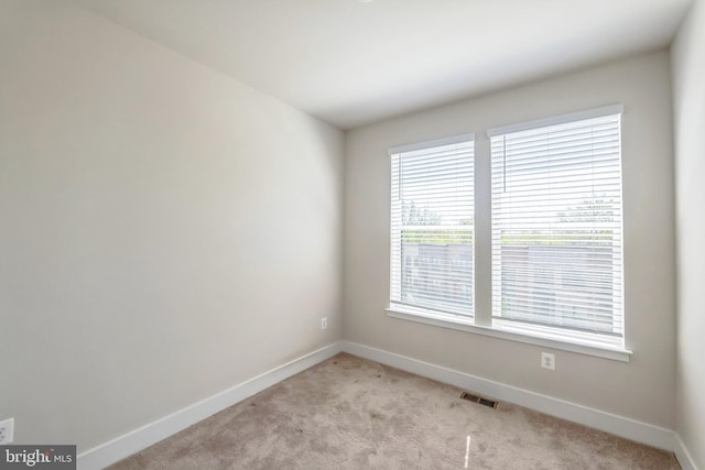 spare room with visible vents, baseboards, and light colored carpet
