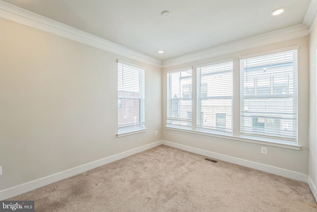 empty room with crown molding, baseboards, visible vents, and carpet flooring