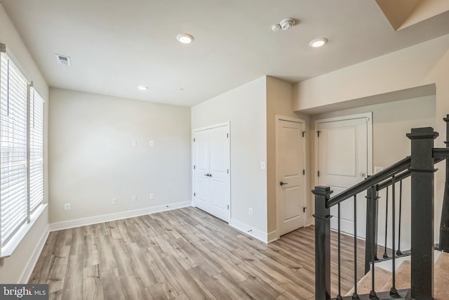 empty room featuring visible vents, stairs, baseboards, light wood-style floors, and recessed lighting