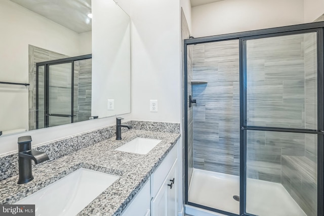 bathroom with double vanity, a sink, and a stall shower